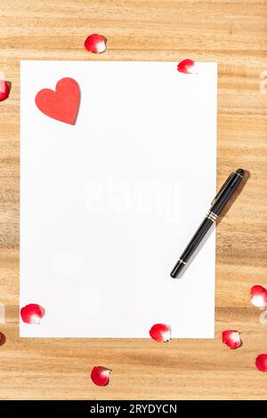 Lettera d'amore. cartellino bianco, a forma di cuore rosso e penna su tavolo di legno Foto Stock