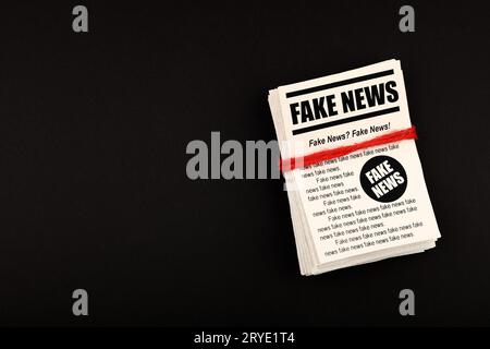 Pila di giornali di NOTIZIE FALSE su nero Foto Stock