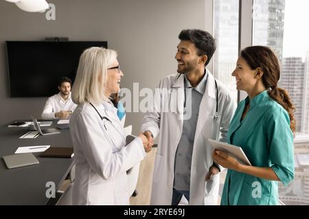 Allegra donna anziana in uniforme bianca che stringe le mani Foto Stock