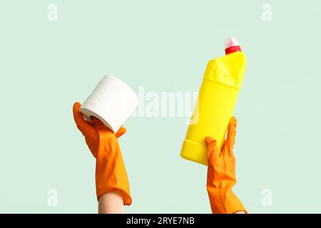 Donna con rotolo di carta igienica e bottiglia di detergente su sfondo verde Foto Stock