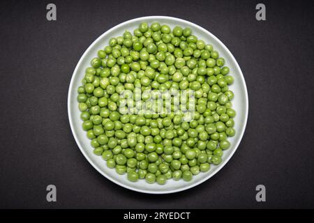 Vista dall'alto di una piastra con pisello verde fresco isolato su sfondo nero Foto Stock