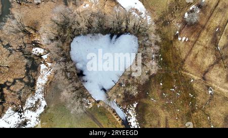 Ripresa aerea con drone di un lago ghiacciato a forma di cuore in baviera Foto Stock