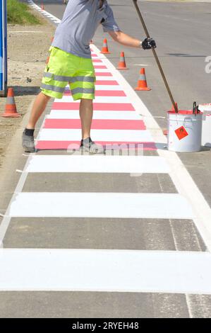 Lavoratore che dipinge il passaggio pedonale per strada Foto Stock