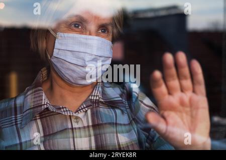 Anziano donna caucasica che indossa la maschera protettiva fatta a mano Foto Stock