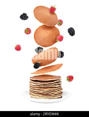 Molti pancake freschi e frutti di bosco che cadono sulla pila su sfondo bianco Foto Stock