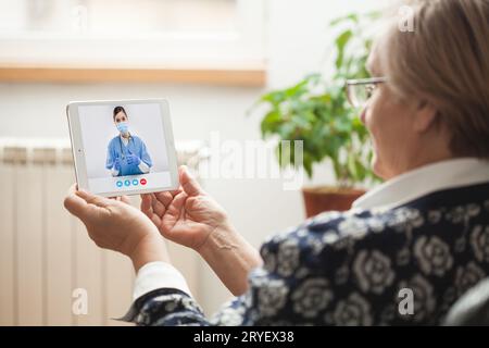 Anziana donna caucasica che parla con una giovane e-Doctor attraverso una video chat online Foto Stock