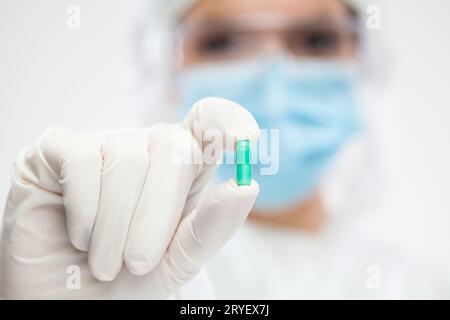 Farmacista donna che indossa dispositivi di protezione individuale (DPI) con pillola verde Foto Stock