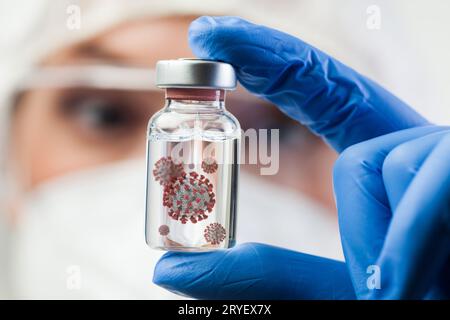 Medico scienziato di laboratorio del Regno Unito che tiene una fiala di vetro contenente una cellula molecolare di coronavirus Foto Stock