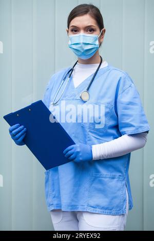 Donna paramedica EMS UK che indossa dispositivi di protezione individuale (DPI) che tiene appunti Foto Stock