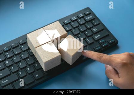 Cubo in legno con logo scudo e segno di spunta sulla tastiera di un computer. Concetto di tecnologia Internet, sicurezza informatica, database e protezione web conce Foto Stock