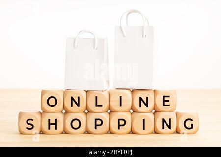 Concetto di shopping online. Testo su blocchi di legno su tavoli e borse di carta. Sfondo bianco. Spazio di copia Foto Stock