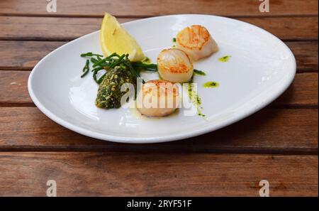 Porzione di capesante grigliate sul piatto sul tavolo Foto Stock