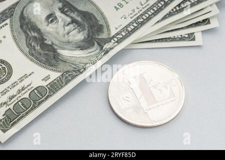 Moneta litecoin e un mucchio di banconote in dollari USA. Blockchain money vs. fiat money Concept Foto Stock