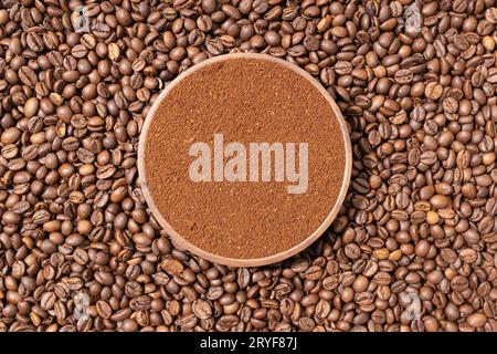 Caffè macinato in una piastra di legno sullo sfondo dei chicchi di caffè. Vista dall'alto Foto Stock