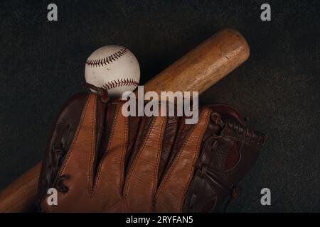 Primo piano di una vecchia palla da baseball, batè in legno e guanto vintage in pelle indossato su sfondo marrone scuro grunge, vista dall'alto elevata, direttamente sopra Foto Stock