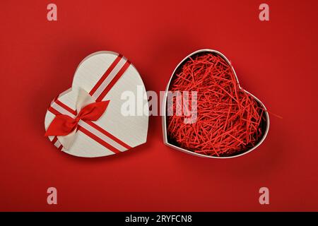 Confezione regalo a forma di cuore aperta su rosso Foto Stock