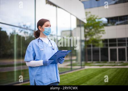 Donna soccorritore in piedi all'ingresso dell'ambulanza che detiene la forma medica del paziente Foto Stock