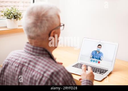 Anziano anziano che parla con una giovane medico femminile tramite una videochiamata portatile Foto Stock