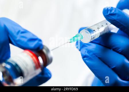 Primo piano dell'ago con la siringa inserita nel flaconcino di vaccino in fiala di vetro Foto Stock