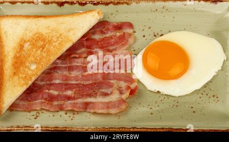 Chiudere l'uovo, il pane tostato e la pancetta sul piatto Foto Stock