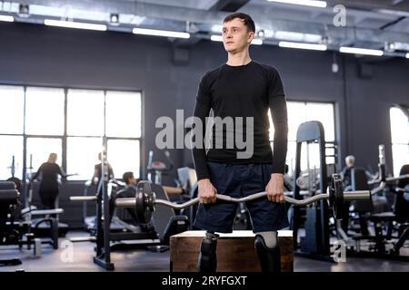 atletico motivato sportivo, forte e stanco, con gambe artificiali che si allenano con il campanello in palestra, foto ravvicinata. tempo libero, tempo libero, stile di vita Foto Stock