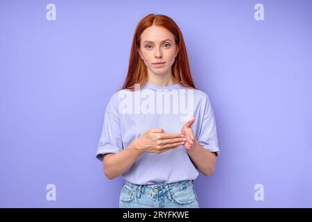 Giovane ragazza dai capelli rossi che lavora come interprete della lingua dei segni , ripresa in studio, ritratto di primo piano sfondo blu isolato 100 numero Foto Stock