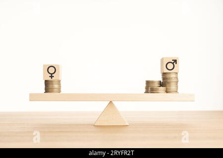 Concetto di divario salariale tra uomini e donne. Blocco di legno con simbolo di genere su monete impilate su una sabuda. Spazio di copia Foto Stock