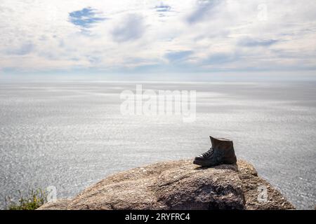 Finisterre, Spagna; 9 giugno 2022: Scarpone in bronzo fuso sulle rocce alla fine di Camino de Santiago. Spazio di copia Foto Stock