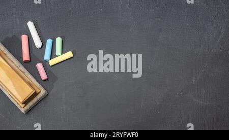 Gruppo di gesso colorato e gomma su lavagna. Spazio di copia. Concetto di ritorno a scuola Foto Stock