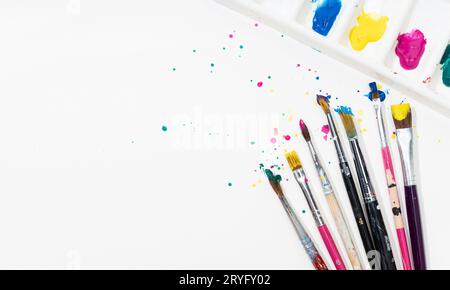 Art Paint pennelli e palette con coloratissimo splatter su carta bianca. Spazio di copia Foto Stock