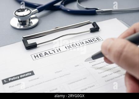 Modulo di assicurazione sanitaria e stetoscopio sulla scrivania Foto Stock