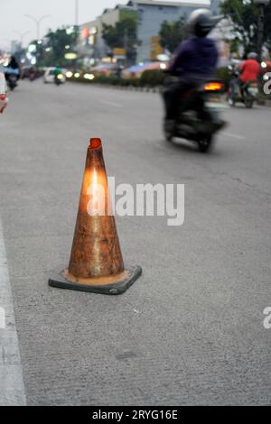 Un posto di blocco arancione vicino alla strada, un cartello per alcune buche sulla strada. Foto Stock