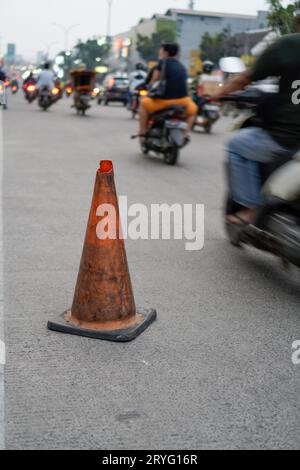 Un posto di blocco arancione vicino alla strada, un cartello per alcune buche sulla strada. Foto Stock