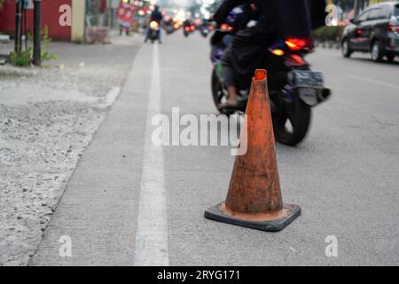 Un posto di blocco arancione vicino alla strada, un cartello per alcune buche sulla strada. Foto Stock