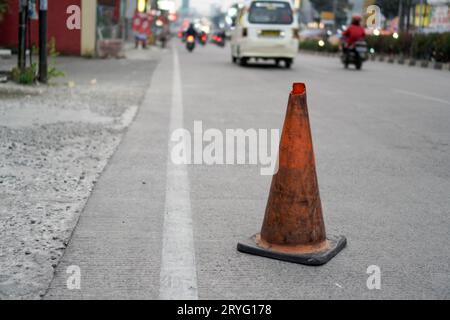 Un posto di blocco arancione vicino alla strada, un cartello per alcune buche sulla strada. Foto Stock