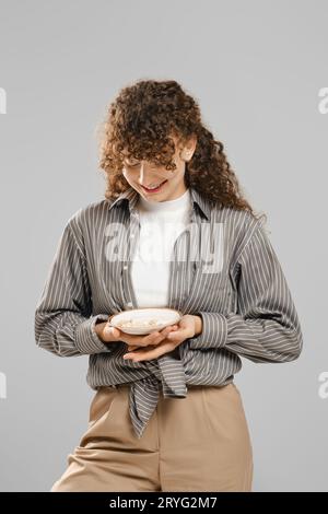 Una donna sorridente tiene in mano un piatto pieno di pillole Foto Stock