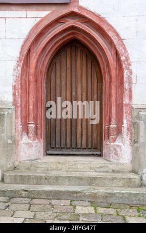 Antica chiesa ad arco porta in legno su un muro di pietra. Foto Stock