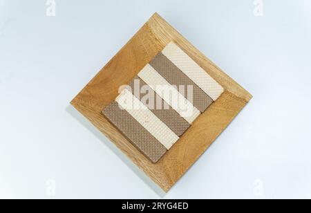 Wafer di formaggio e wafer di cioccolato serviti su un piatto di legno isolato su sfondo bianco Foto Stock