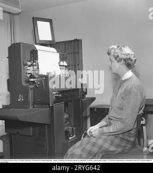 Negli anni '1950 Un impiegato di sesso femminile al lettore di schede perforatrici che si affaccia sul suo funzionamento e l'alimentazione delle schede perforatrici nella macchina. Le schede perforate sono state create da un'altra macchina, immettendo le informazioni, creando le schede perforate come supporto di memorizzazione in cui i fori perforati nella scheda di carta erano le informazioni di input. L'immagine mostra la macchina che legge le informazioni dalle schede di perforazione, quindi le stampa. La macchina è prodotta dal produttore britannico Powers-Samas, che ha sviluppato la macchina di cifratura, molto meglio e più sicuro della tedesca Enigma. Svezia 1954. Kristoffersson rif. BM85-10 Foto Stock