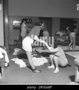 Ginnastica in passato. In una palestra, un gruppo di donne si inginocchiano e allungano le braccia in un movimento. Le giovani donne si prendono una pausa dal lavoro e fanno ginnastica durante l'orario di lavoro. La ginnastica da ufficio era un'invenzione moderna negli anni '1940, quando l'assistenza sanitaria per i dipendenti cominciò ad essere implementata. Svezia 1949. Kristoffersson rif. AX72-5 Foto Stock