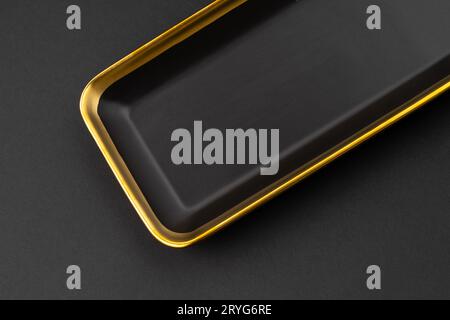 Un set di piastre in ceramica nera e dorata su sfondo nero Foto Stock