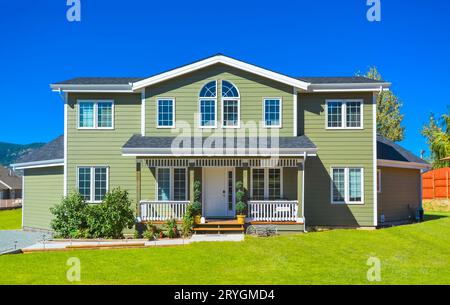 Grande casa di famiglia con un sentiero che porta alla porta di fronte e un cielo blu sullo sfondo. Foto Stock