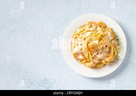 Pasta di pesce. Pappardelle con gamberetti e salsa alla panna in un piatto bianco Foto Stock