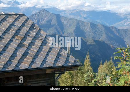 tetto con piastrelle di pietra, tipico delle case di montagna, pietre di granito grigio blu, montagne sullo sfondo. isolamento termico, classe energetica. Foto Stock