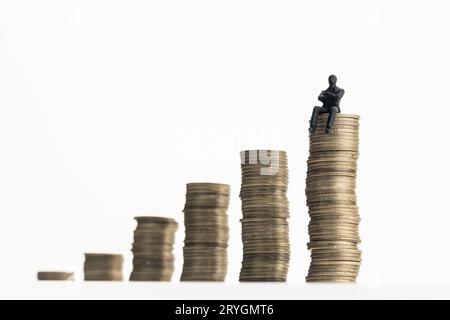 Uomo in piedi su una pila di monete in crescita Foto Stock