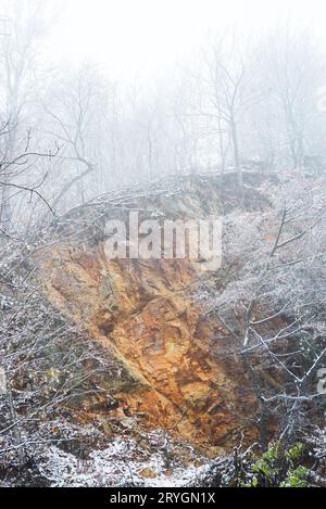 Rocce arancioni dopo una piccola frana nella foresta invernale Foto Stock