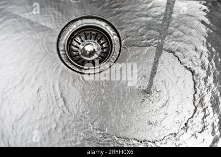 L'acqua scarica un lavandino in acciaio inox Foto Stock