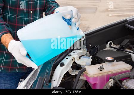 versare l'antigelo. il conducente versa il liquido nel serbatoio del liquido lavavetro. liquido lavavetri. detergente per vetri. uomo che versa il tergicristallo nell'auto. il conducente versa un Foto Stock