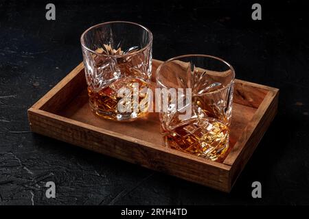 Whiskey in bicchieri con ghiaccio. Whisky bourbon su rocce su fondo scuro Foto Stock