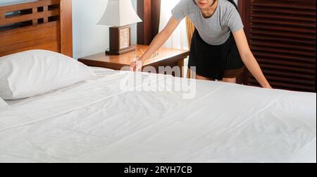 Cameriera professionale e giovane che prepara il letto in camera Foto Stock